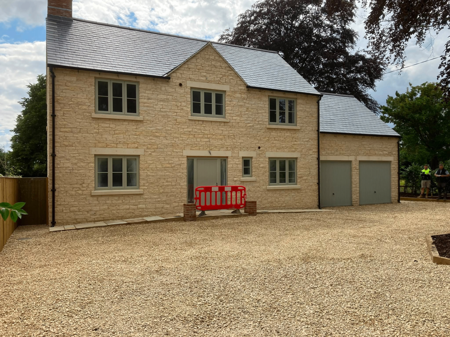 Completed Cotswold-stone family home with slate roof and integral double garage, built by DR Smith Building.