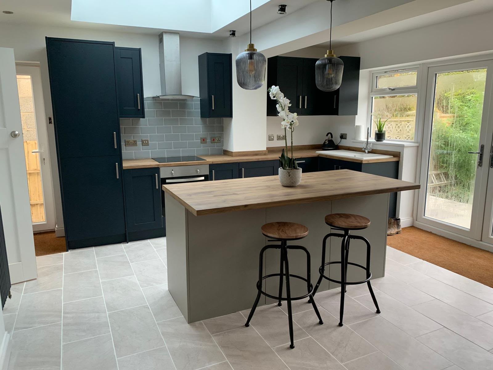Open-plan kitchen extension with navy shaker units, oak worktops and central island, completed by DR Smith Building.