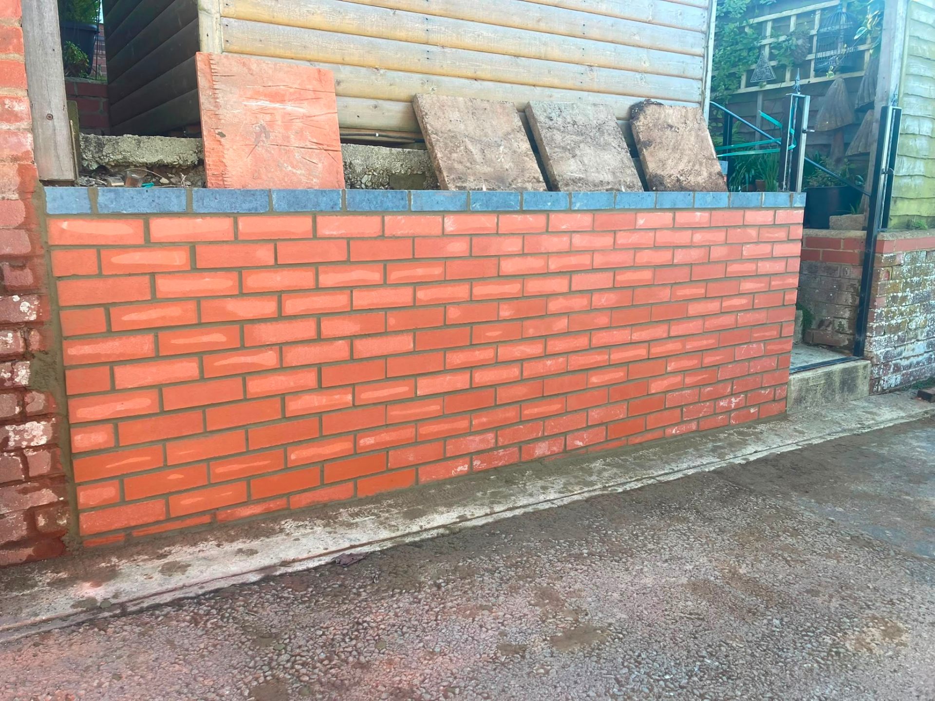 Freshly laid red brick garden wall with blue engineering brick coping in Swindon by DR Smith Building.