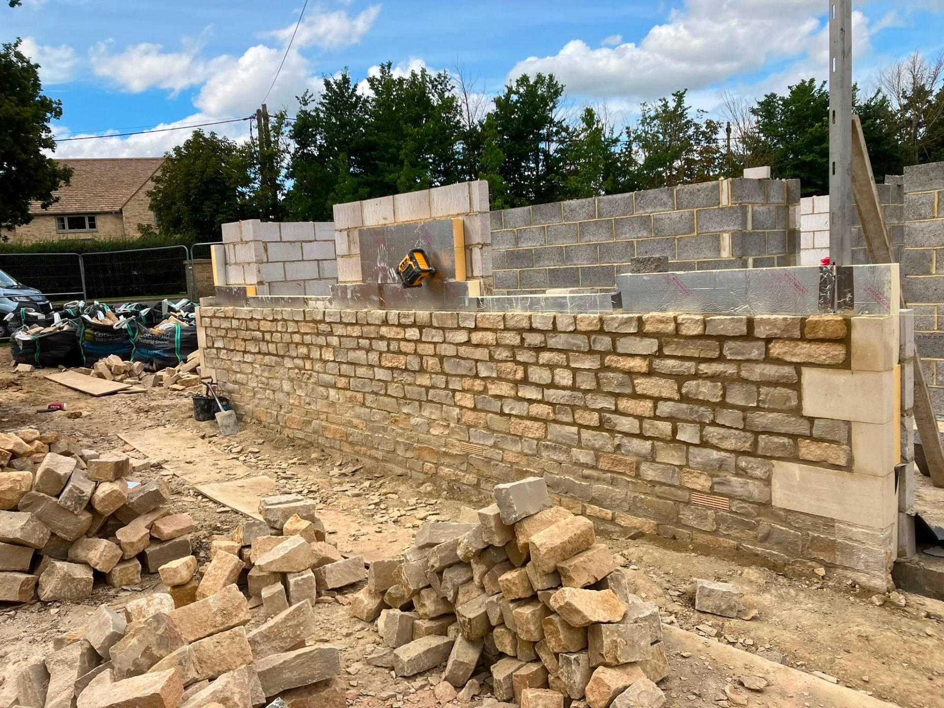 Partial stone wall with materials on site by DR Smith Building.